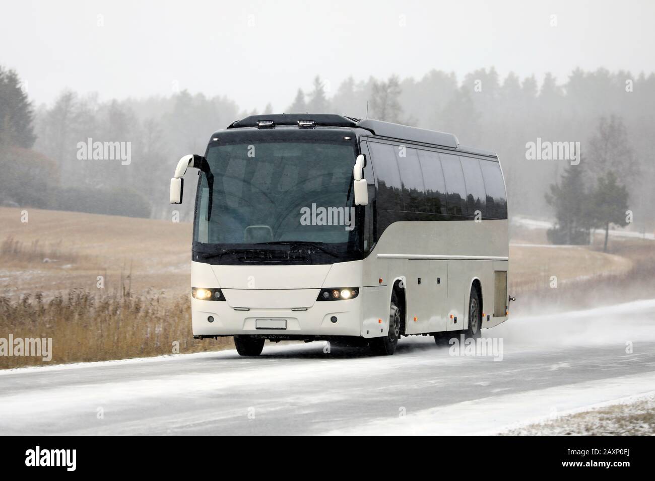 Weißer Reisebus, der im Winter auf der Landstraße unterwegs ist. Stockfoto