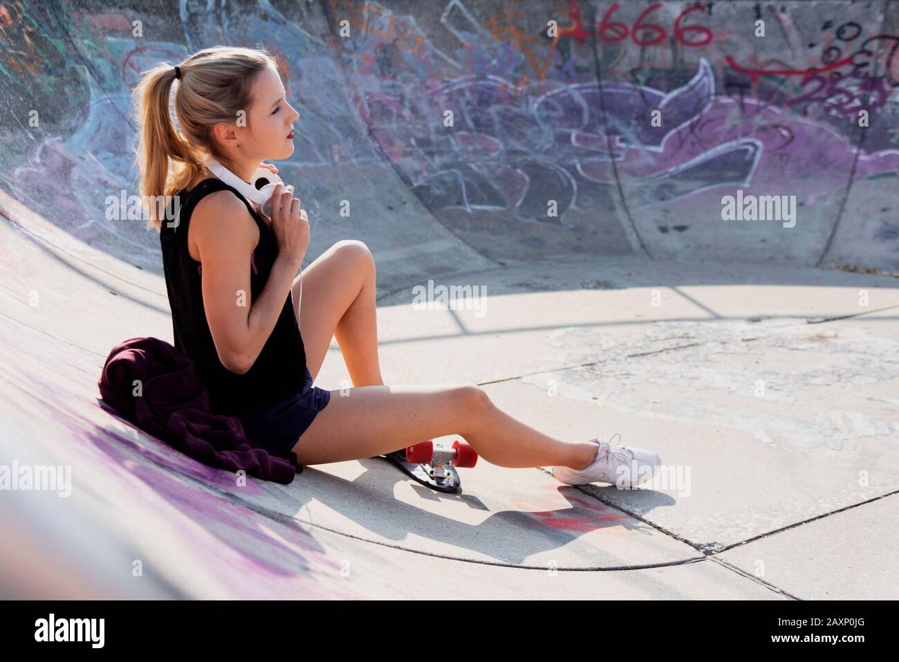 Junge Frau sonnt sich auf Betonrampe im Skatepark Stockfoto