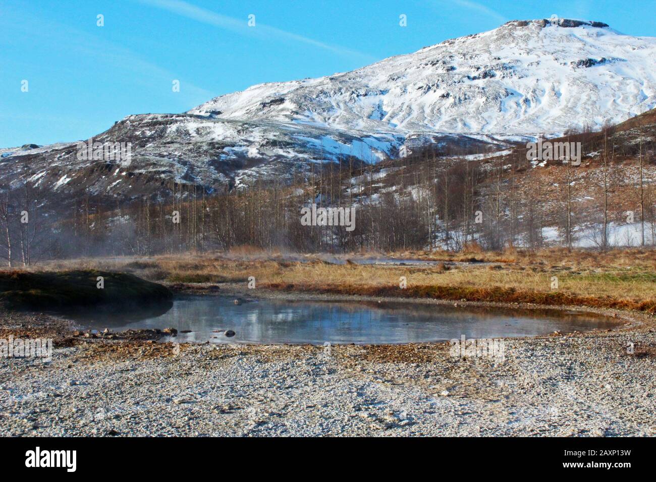 Atemberaubender schneereichter Berg und heißer Frühling im Geysir Park, Island an einem hellen Tag Stockfoto