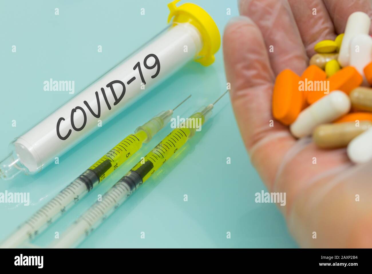 COVID-19 in einer Durchstechflasche Hand in Gummihandschuh mit Medikamenten und Injektionen. Konzept der Arbeit an einem Virusimpfstoff Stockfoto