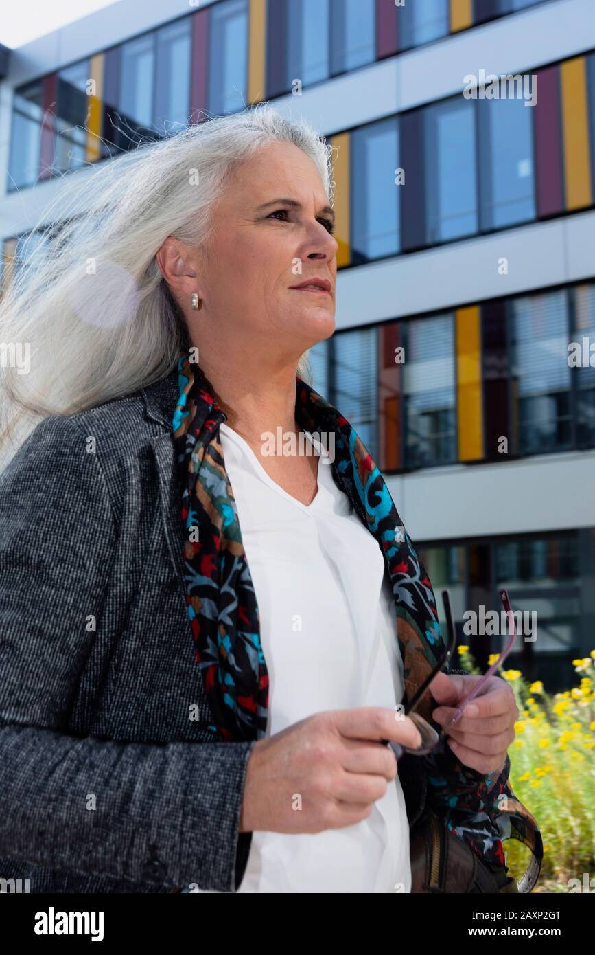 Geschäftsfrau mittleren Alters vor modernem Bürogebäude, halb Porträt Stockfoto