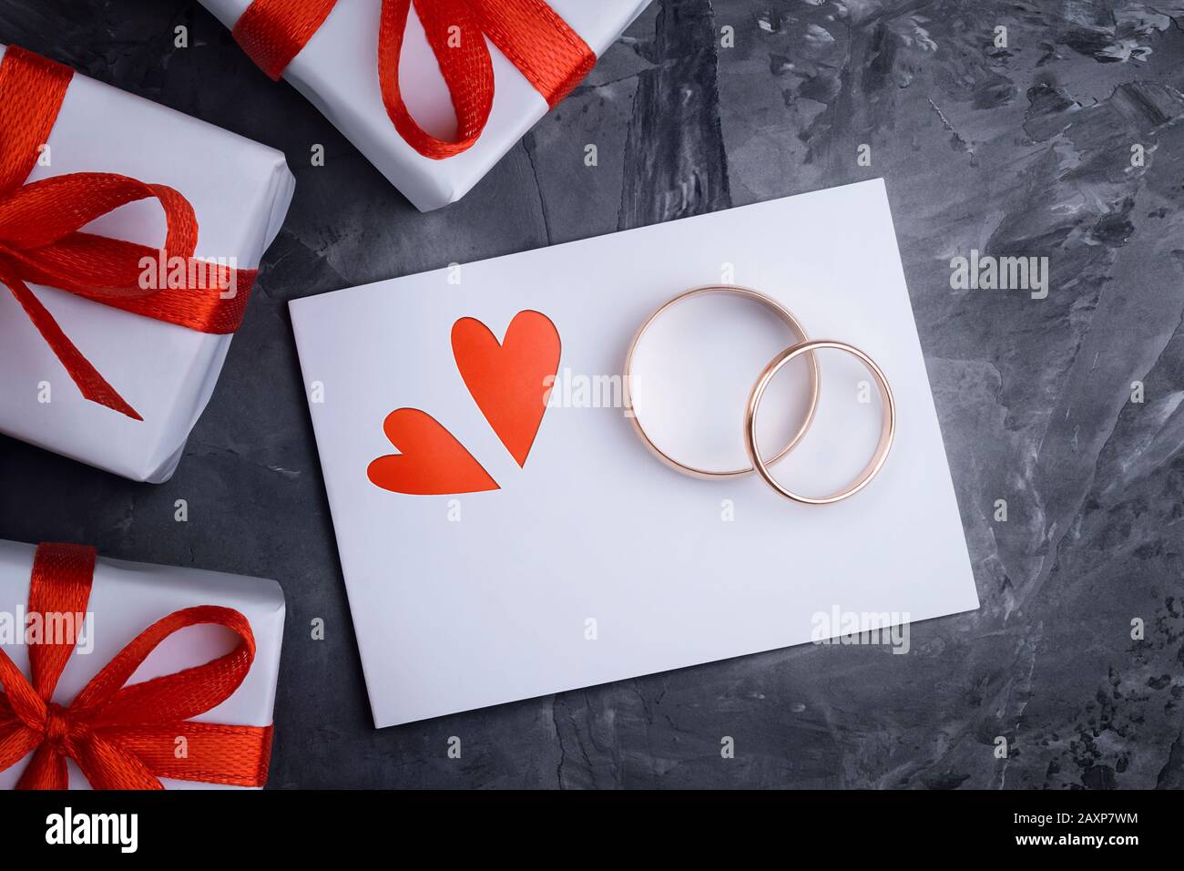Blick auf eine grußkarte zum valentinstag mit zwei eleganten kreativen Herzen, zwei goldenen Hochzeitsringen, Geschenkschachteln mit rotem Band Stockfoto