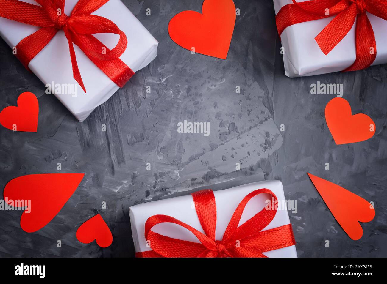 Valentinstag Grußkarte Vorlage von drei weißen Geschenkschachteln mit rotem Band mit Schleife und mehreren roten Herzen verschiedener Formen Stockfoto