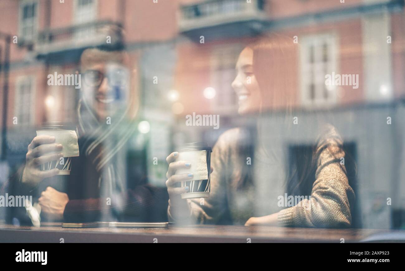 Junges glückliches Paar in der Kaffeebar, das Cappuccino trinkt und Spaß mit dem Handy hat - Fröhliche Leute genießen Zeit zusammen mit neuer Sozialtechnik Stockfoto