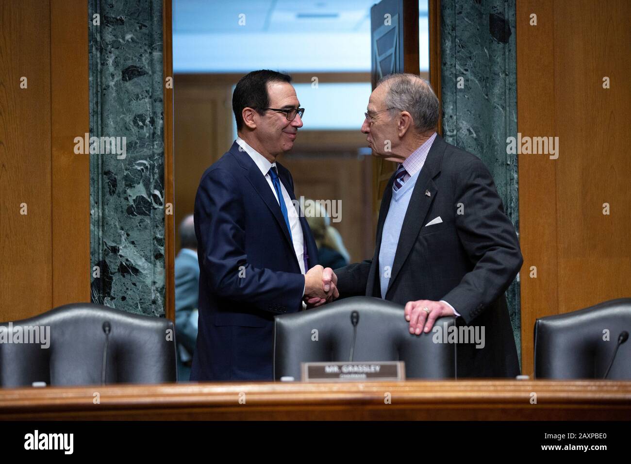 US-Finanzminister Steven T. Mnuchin schüttelt mit dem US-Senator Chuck Grassley (Republikaner von Iowa) die Hände, als er eintrifft, um vor dem US-Senatsausschuss für Finanzen über das Budget für das Geschäftsjahr 2021 im United States Capitol in Washington D.C. zu Aussagen, USA am Mittwoch, Februar 2020. Kredit: Stefani Reynolds / CNP / MediaPunch Stockfoto