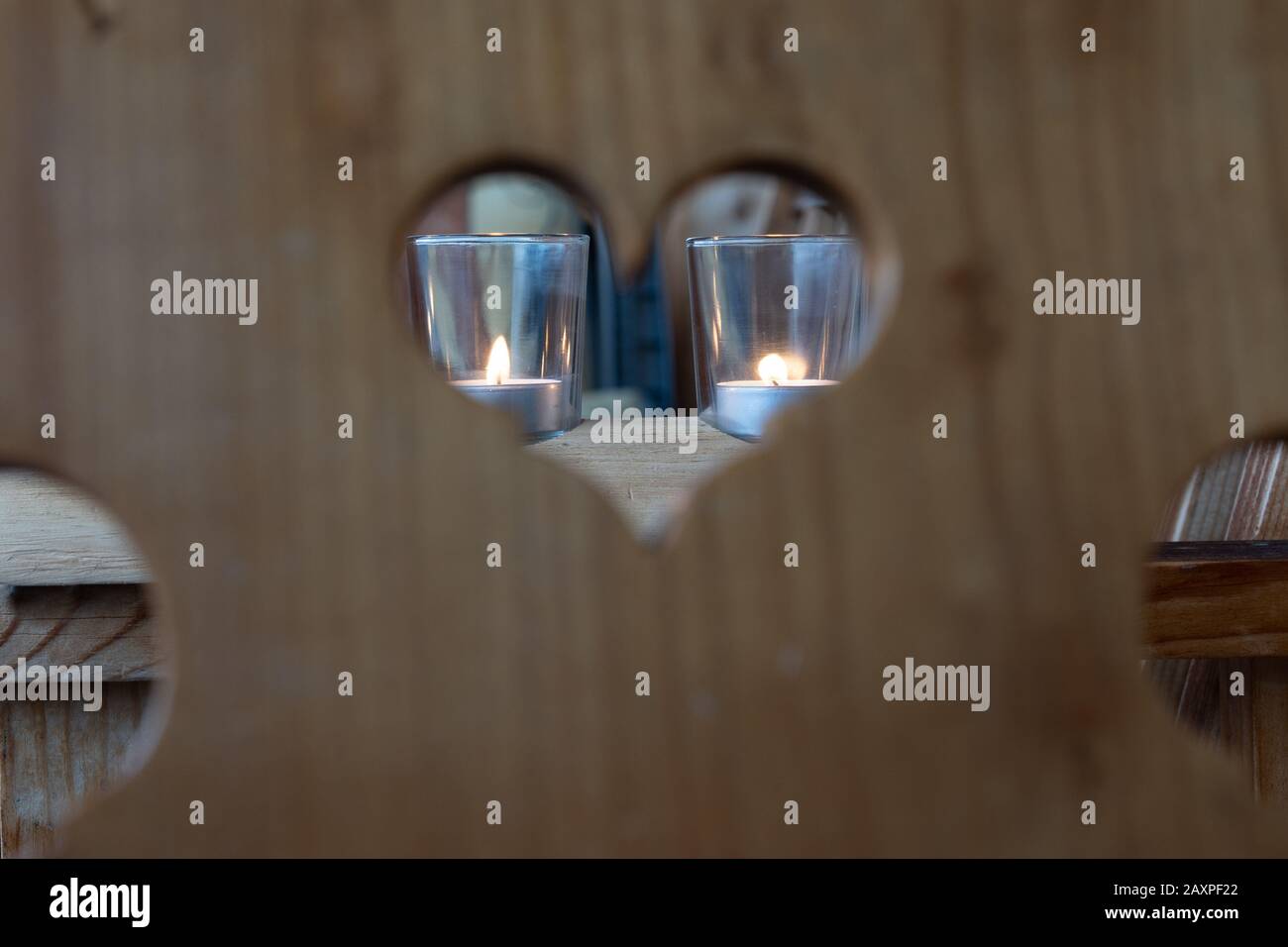 Valentinstag herzförmige Rahmen, Peephole im Holzstuhl, Kerzenglas im Hintergrund, Nahaufnahme. Stockfoto