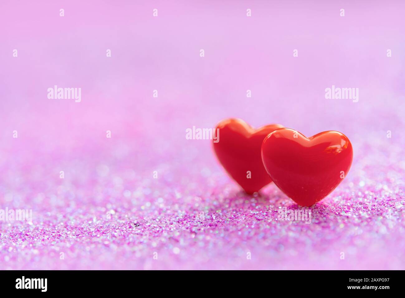 Valentines Day Hintergrund mit Red Heart Shapes auf abstraktem hellrosa Glitzerhintergrund, Copy Space Stockfoto
