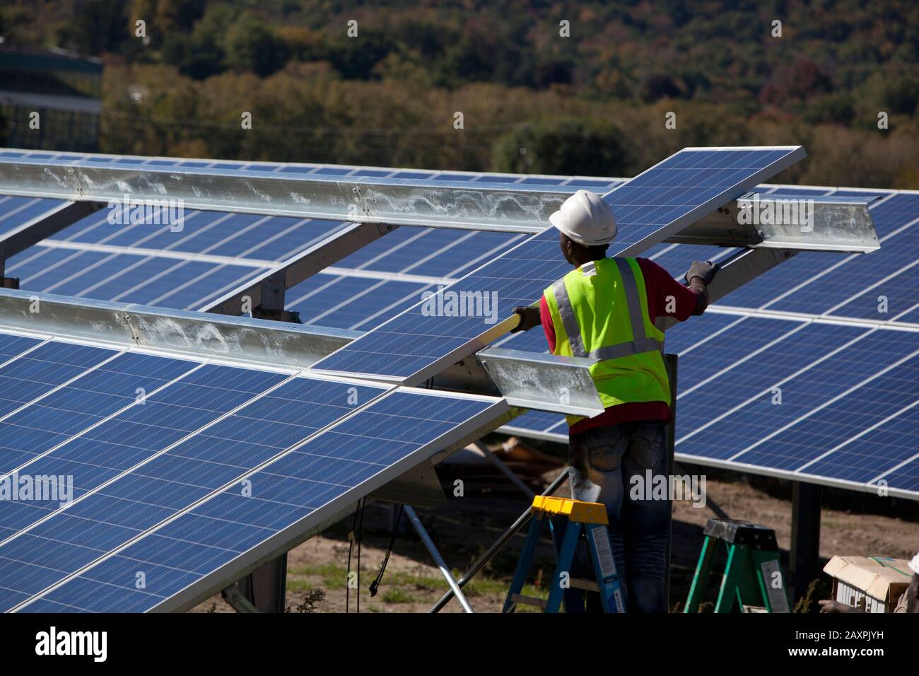 Arbeiter, die eine Reihe von Solarpaneelen in einem offenen Feld im Süden von Vermont installieren Stockfoto
