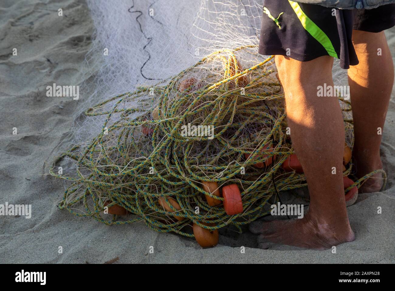 Puerto Escondido, Oaxaca, Mexiko - Fischer falten ihre Netze, nachdem sie ihre Fänge im Morgengrauen am Hauptstrand von Puerto Escondido verkauft haben. Stockfoto