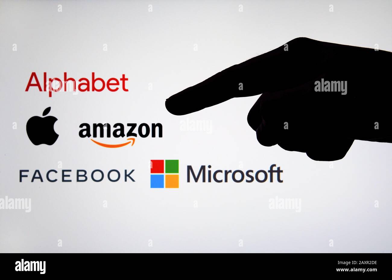 Big Tech Firmenlogos: Alphabet, Amazon, Apple, Facebook und Microsoft auf einem unscharfen Bildschirm und einer Silhouette der Hand. Kartellrecht und Regulierung. Stockfoto