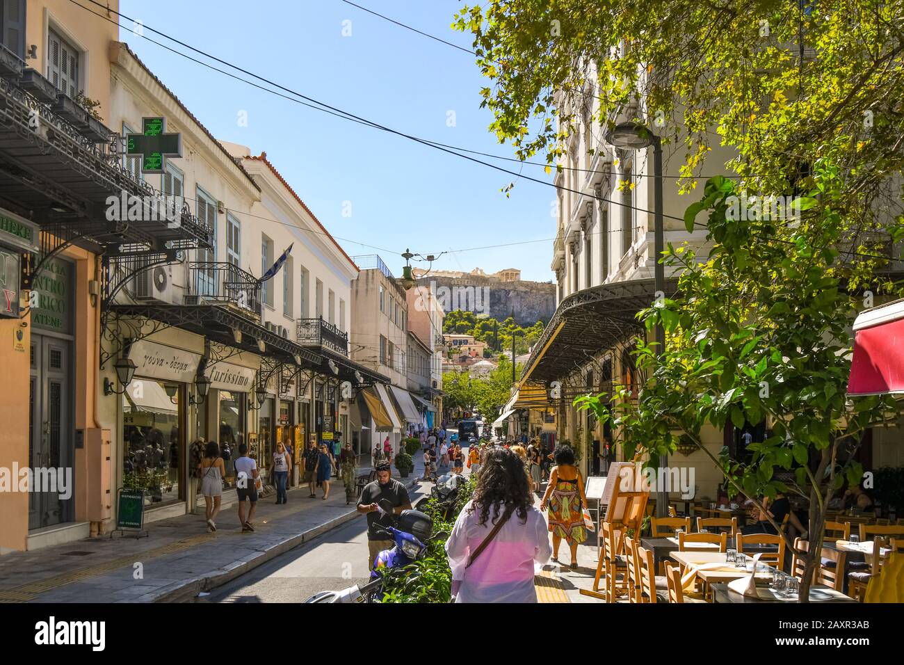 Touristen kaufen und besichtigen in der Gegend Plaka in Athen Griechenland mit dem Parthenon und dem Akropolis-Hügel in der Ferne. Stockfoto