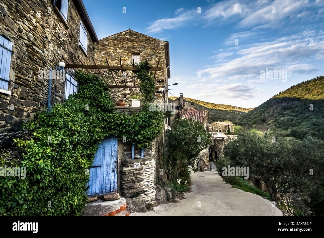Dorf in der Nähe von Roquebrun. Der Weiler liegt direkt auf dem schwarzen Schiefer des Berges. Die Häuser bestehen aus demselben Material. Stockfoto