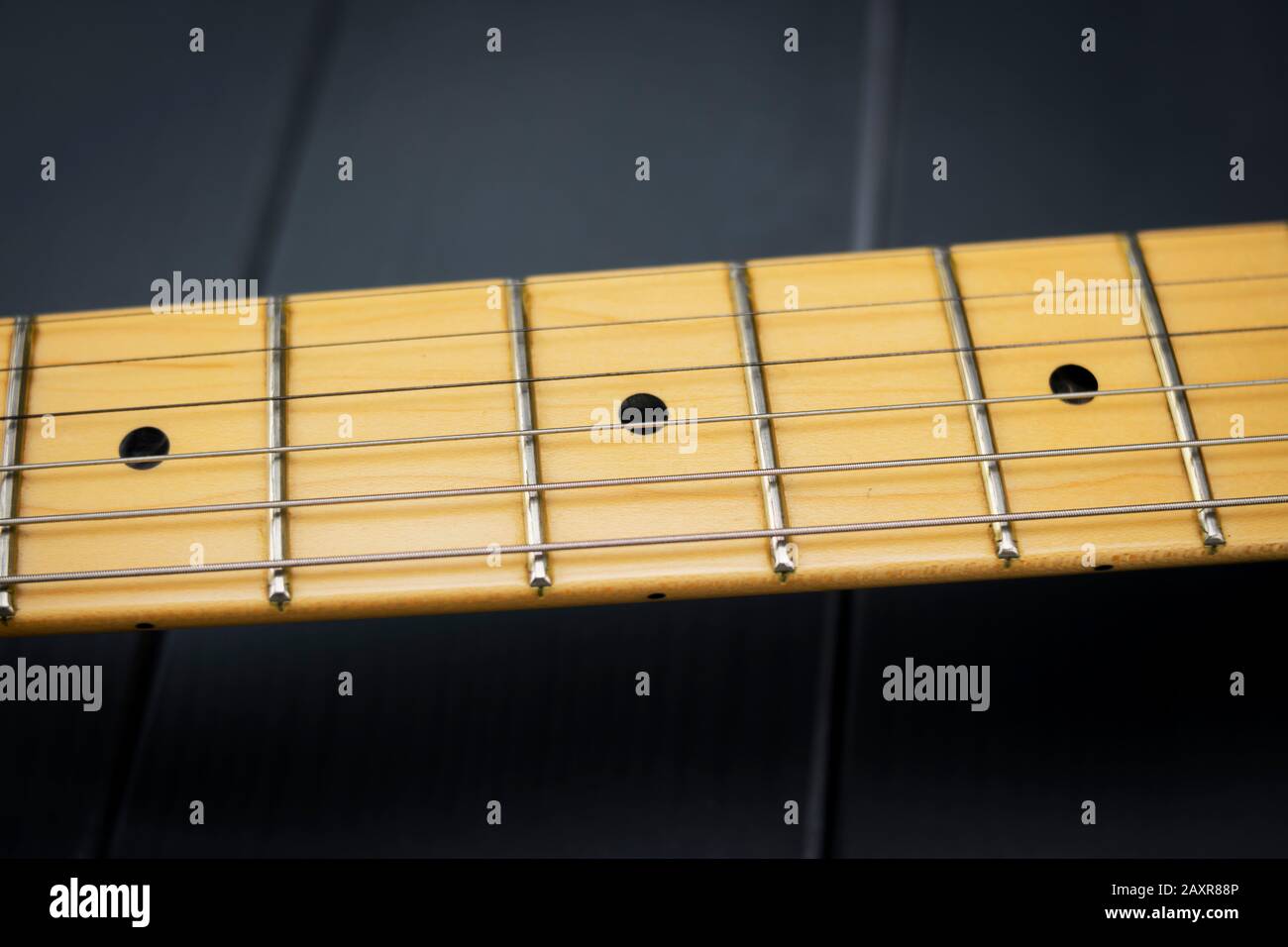 Griffbrett einer lackierten E-Gitarre, mit hellen Saiten und punktförmigen Markierungen, um die Zahl der Bünde zu identifizieren Stockfoto