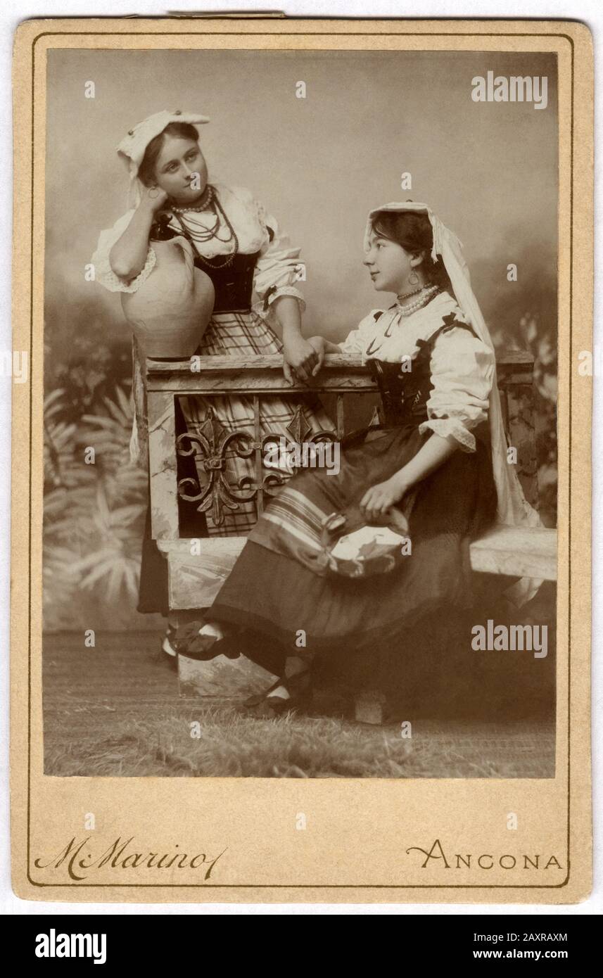 Ca, ANCONA, ITALIEN: Porträt der italienischen Frauen im Folkkostüm der REGION MARKEN . Foto von M. MARINO, Ancona . Der marinesische Fotograf, nachdem er offizieller Fotograf des Herzog von Genua Savoia geworden war, zog von Ancona ( Piazza Plebiscito, 5 ) nach Rom ( Via dei Serpti, 74 ). 1918.- PORTRÄT - RITRATTO - GESCHICHTE - FOTO STORICHE - ITALIEN - OTTOCENTO - 800 - 800 - KOSTÜM FOLKLORISTICO REGIONALE - FOLKLORE - MODA - MODE - donna - Donne - Schuhe - Scarpe bianche - Hut - cappello - anfora - Tamburello - Mano nella mano - Hand in Hand - amiche - Freunde - amicizia - friendshi Stockfoto