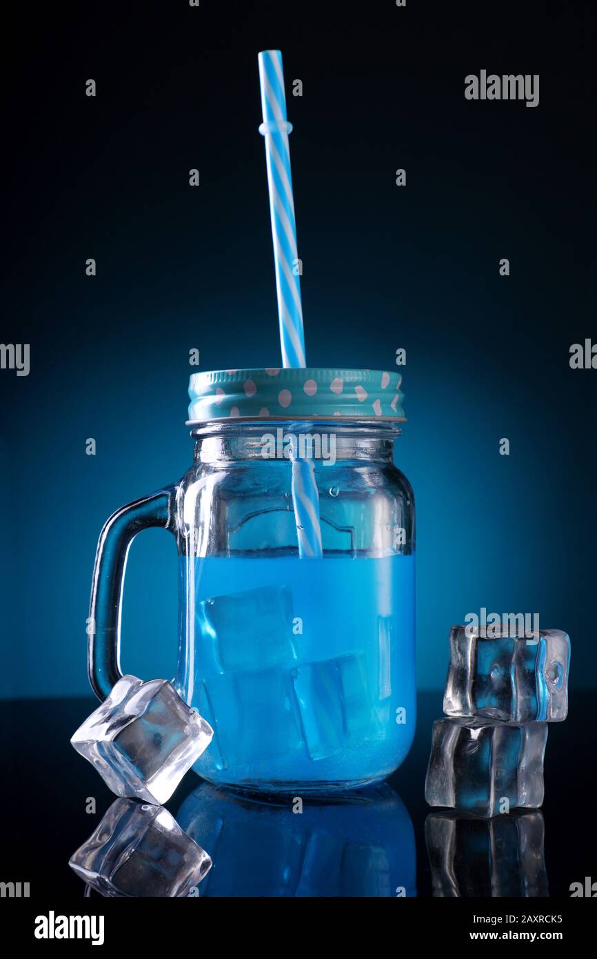 Blau Gefärbter Cocktail in einem Mason-Mixbecher mit Strohhalm- und Eiswürfel Stockfoto