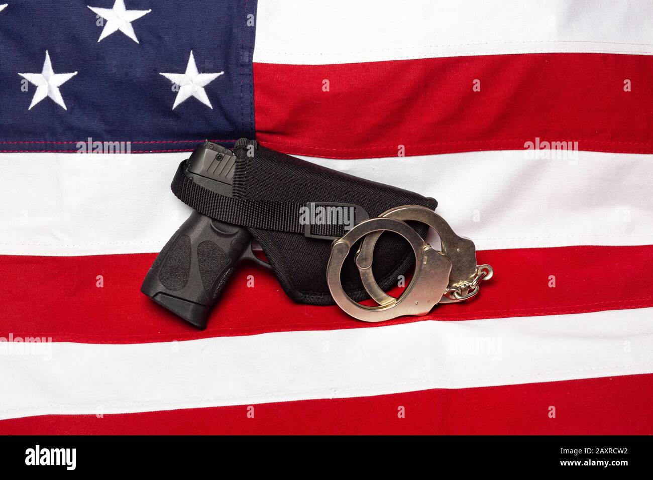 Pistole, Holster und Handschellen vor der amerikanischen Flagge, horizontal Stockfoto