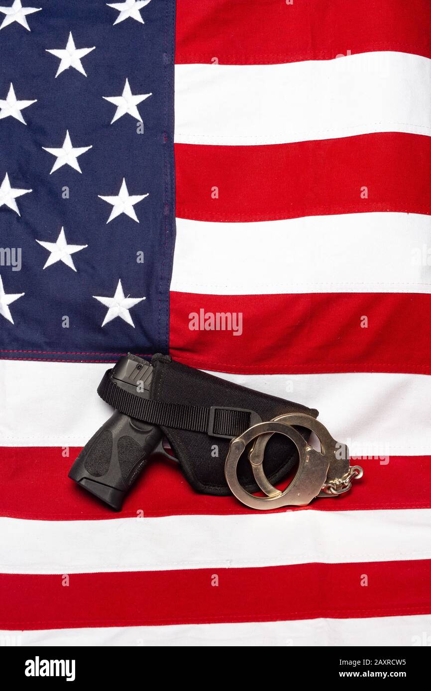 Pistole, Holster und Handschellen vor der amerikanischen Flagge, senkrecht Stockfoto