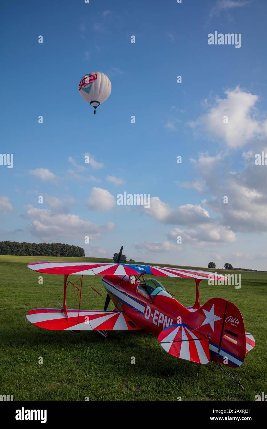 Pitts S1-E Doppelflugzeug auf einer Wiese, Heißluftballon in der Luft, Luftschau, Flugplatzfest Degerfeld, Schwäbische Alb, Deutschland Stockfoto