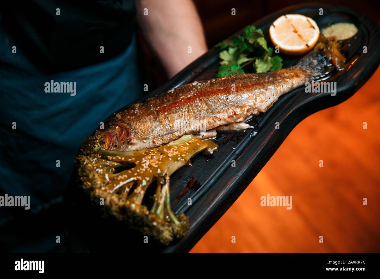 Gebackene Fische mit Zitrone liegen auf einem schwarzen Brett. Stockfoto