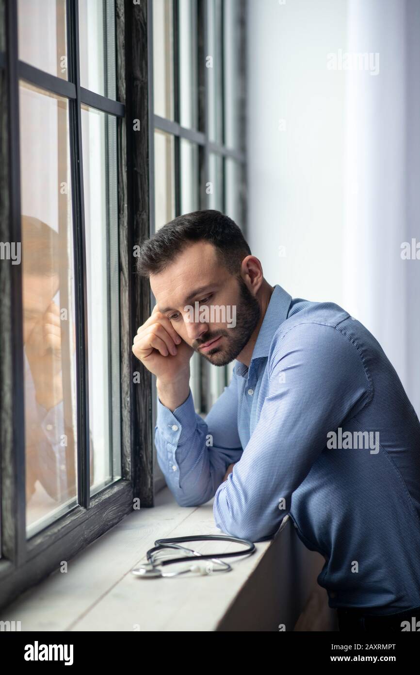 Junger bärtiger Mann in blauem Hemd, der betont aussieht Stockfoto