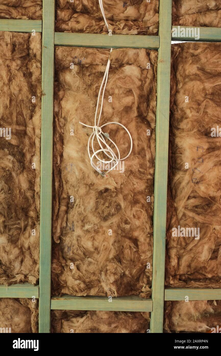 Holz-Stehbolzen-Wandrahmen mit Elektrokabel und freiliegenden Glasfaser-Isolierschlägern. Ein vertikales Rechteck der Wand, das im Detail dargestellt wird Stockfoto