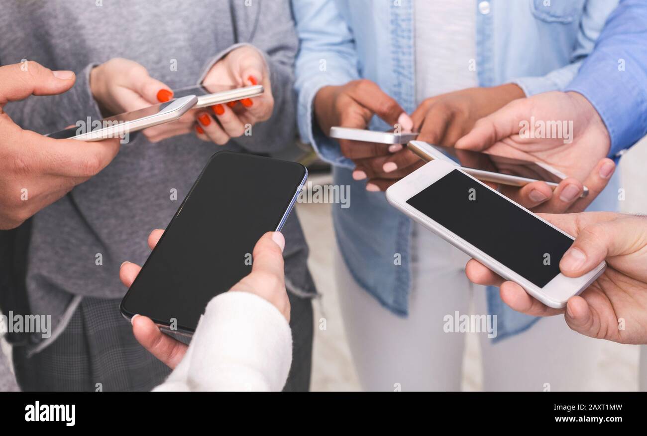 Gruppe von nicht erkennbaren Freunden, die Smartphones mit schwarzem Bildschirm verwenden und Medien freigeben Stockfoto