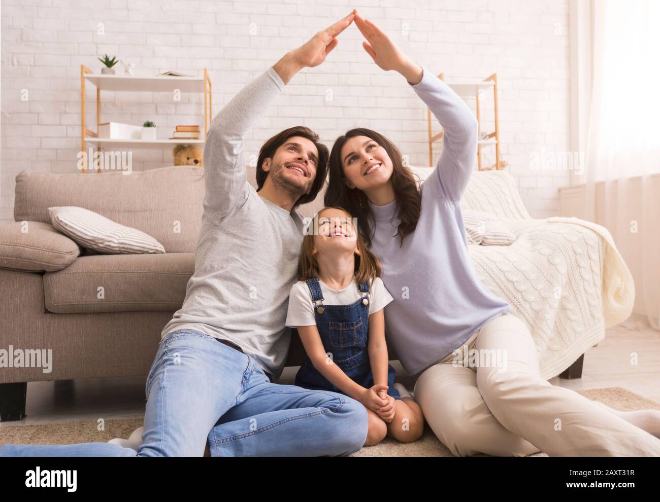 Fürsorgliche Eltern machen symbolisches Handdach über dem Kopf der kleinen Tochter Stockfoto