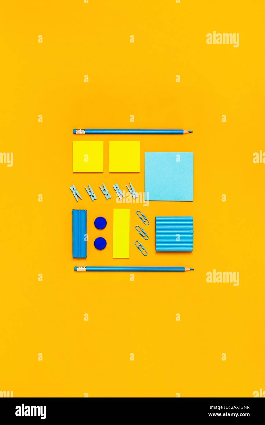Gelber Hintergrund mit gelben und blauen Schreibmaterialien für Schule und Universität. Flaches Layout, Draufsicht, Kopierbereich. Stockfoto
