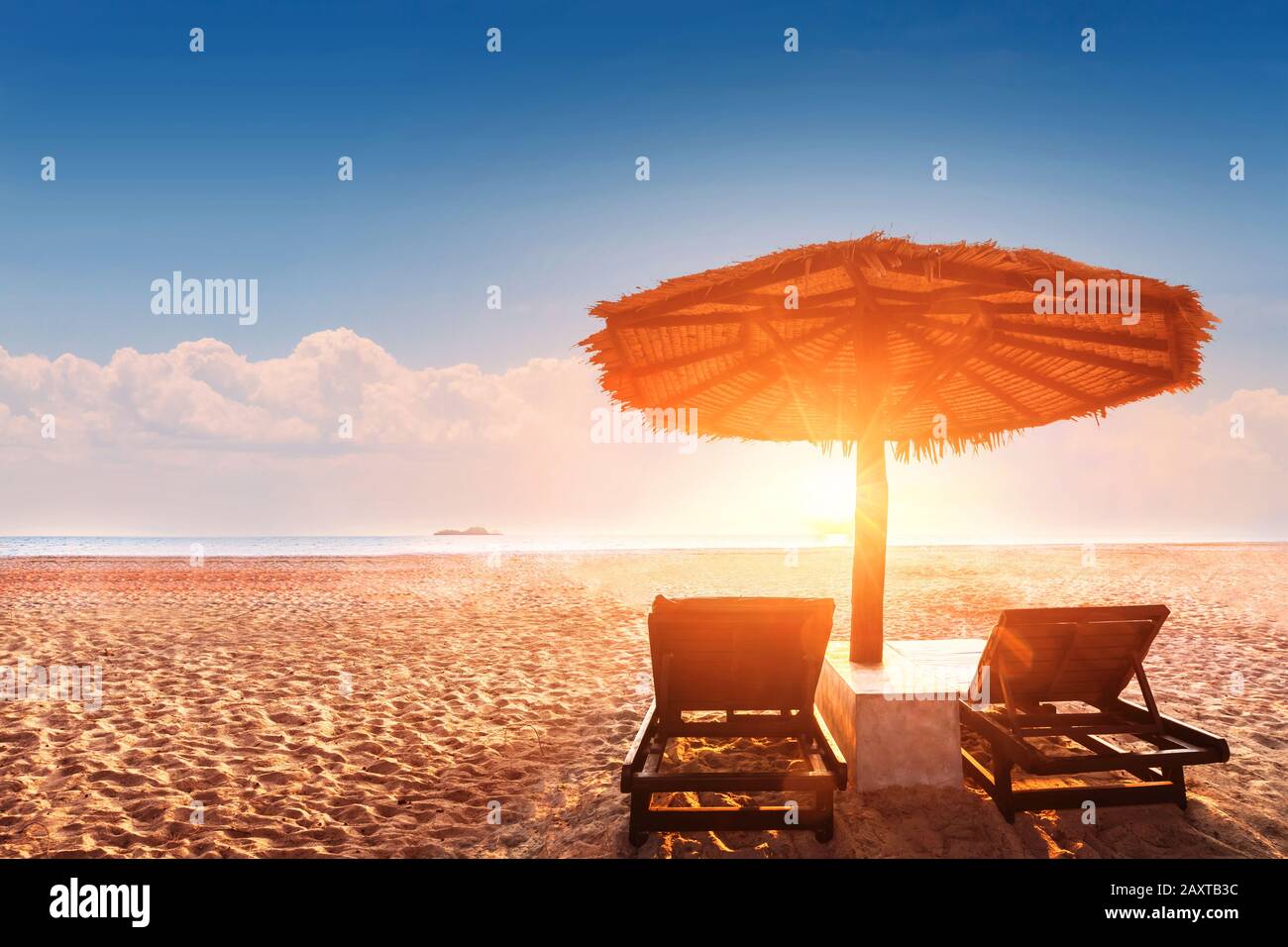 Sonnenschirm und Sonnenliegen am leeren tropischen Strand bei Sonnenuntergang mit schönen warmen Farben, Sommerurlaub Urlaubsziel Hotelresort Landschaft Stockfoto