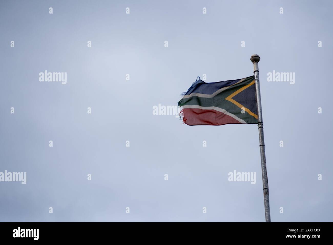 Verwelkte und auf dem Kopf stehende Flagge Südafrikas auf Fahnenmast Stockfoto