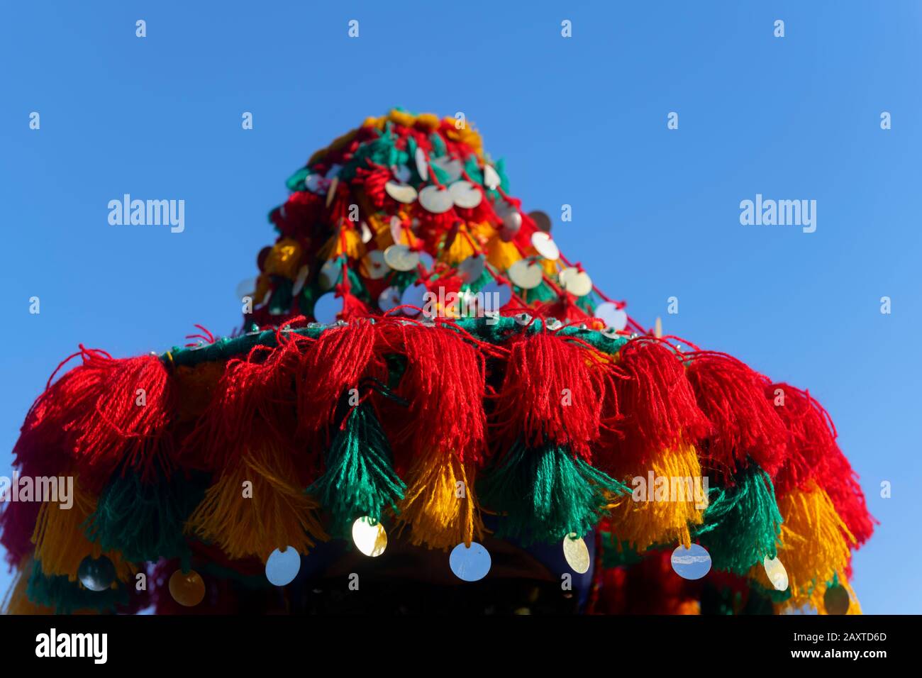 Kultiger, bunter Hut eines traditionellen Wasserverkäufers in Marrakesch, Marokko, gegen den blauen Himmel. Stockfoto
