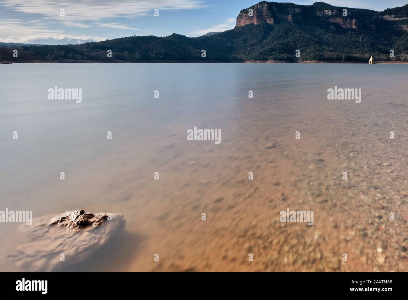 Stein in transparentem Wassersumpf und aus dem Wasser ragende Glocke, Katalonien Stockfoto