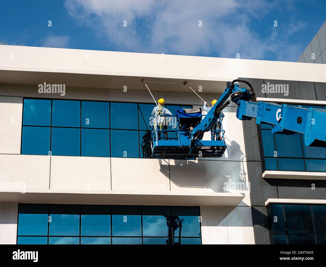 Singapur - 26. DEC 2019 - Nahaufnahme von Bauarbeitern in einem Metallkorbgemälde und Reinigung des äußeren eines Industriegebäudes Stockfoto