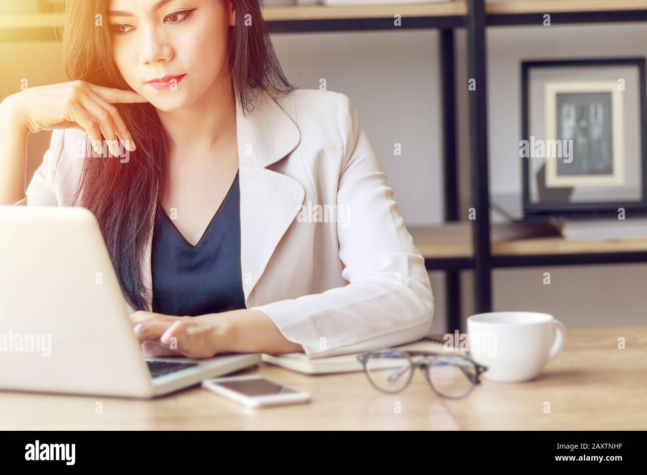Junge asiatische Geschäftsfrau bei der Arbeit. Schöne asiatische Frau im lässigen Anzug Arbeit mit Computerlaptop im modernen Büro. Freiberuflich und im Start Stockfoto