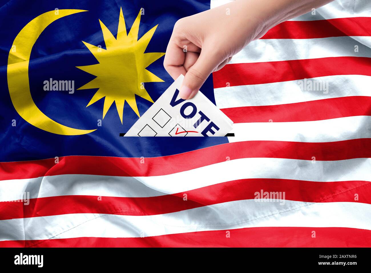 Malaysia General Election Concept. Nahaufnahme einer Person, die während der Wahlen auf der Leinwand einen Wahlzettel ablegt. Hintergrund der Flagge von Malaysia. Stockfoto