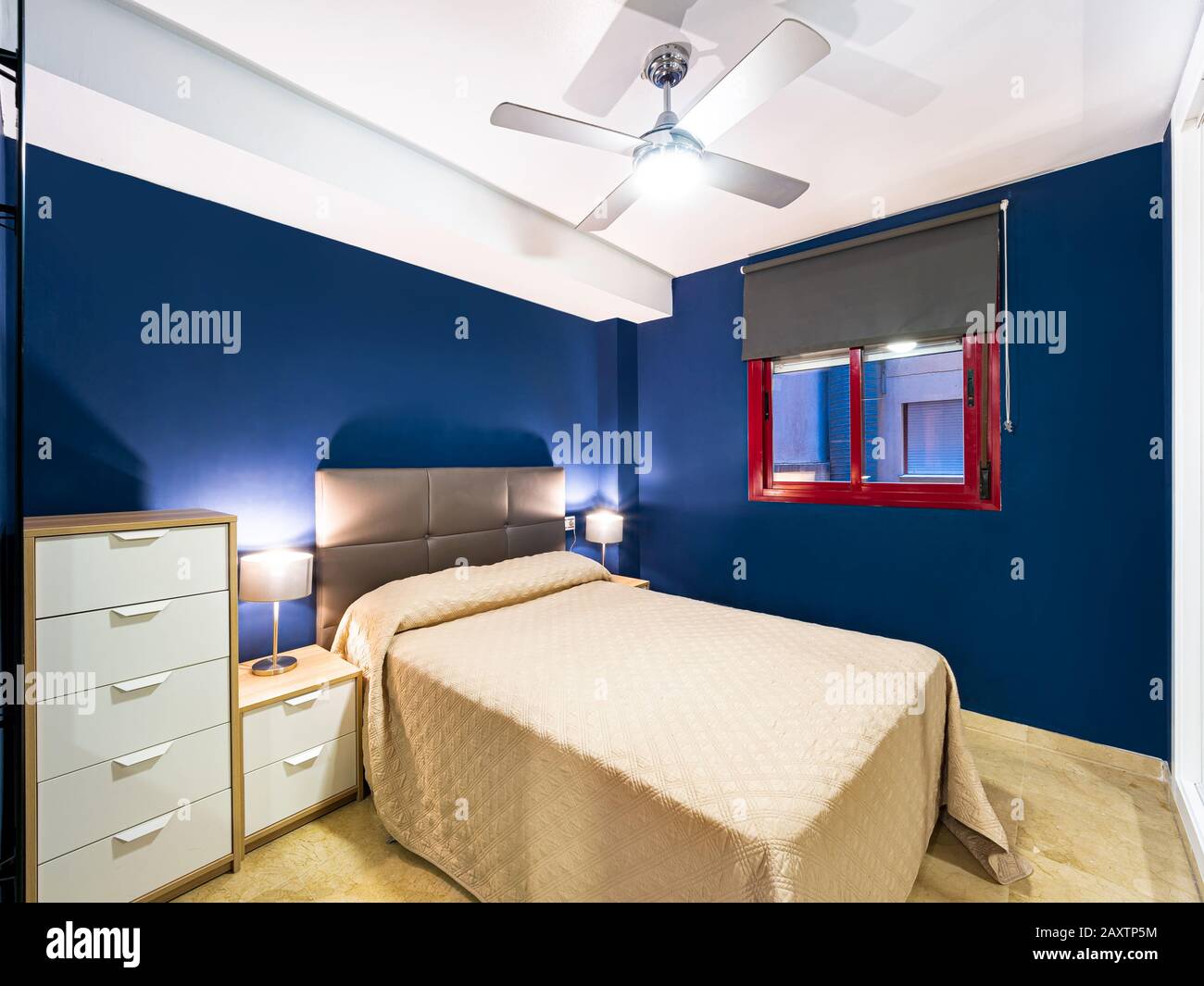 Komfortables Hotelzimmer mit Kopfteil aus Stoff mit Federdecke aus Naturstoff, Lampen, Nachttisch aus Holz und einem großen Spiegel. Holiday Destination Apartment Stockfoto