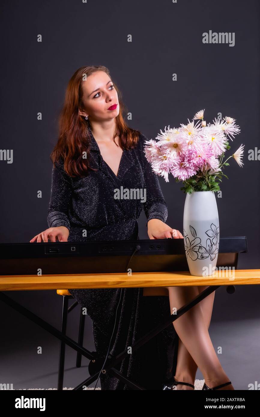 Inspiriert von Herbstblumen, komponiert eine Frau Musik auf einem elektronischen Klavier Stockfoto