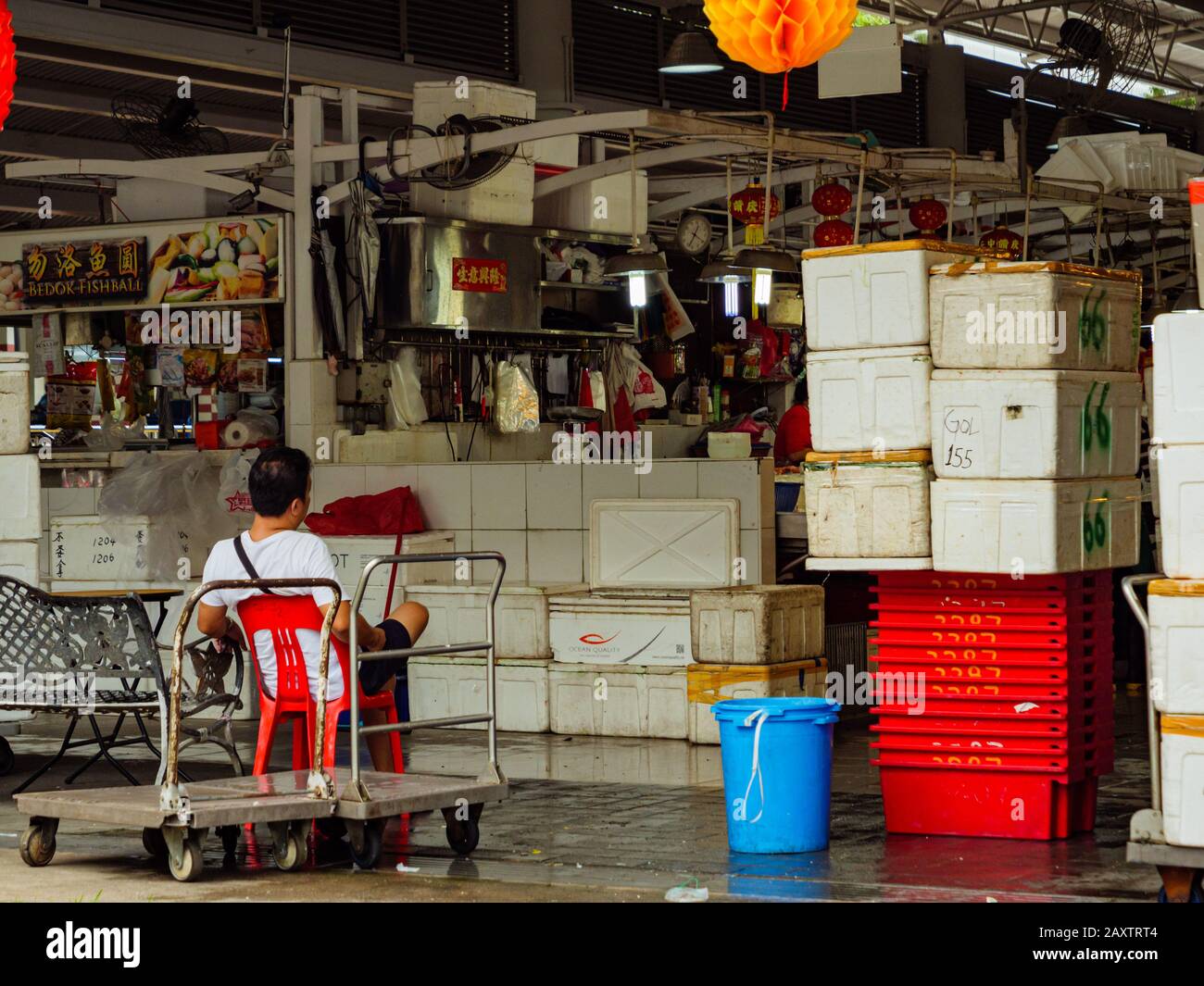 Singapur - 4. JANUAR 2020 - EIN Fischhändler, der eine Ruhepause in einem integrierten Wet Market and Hawker Center in Ang Mo Kio, Singapur unternimmt. Die chinesischen Wörter zu Stockfoto