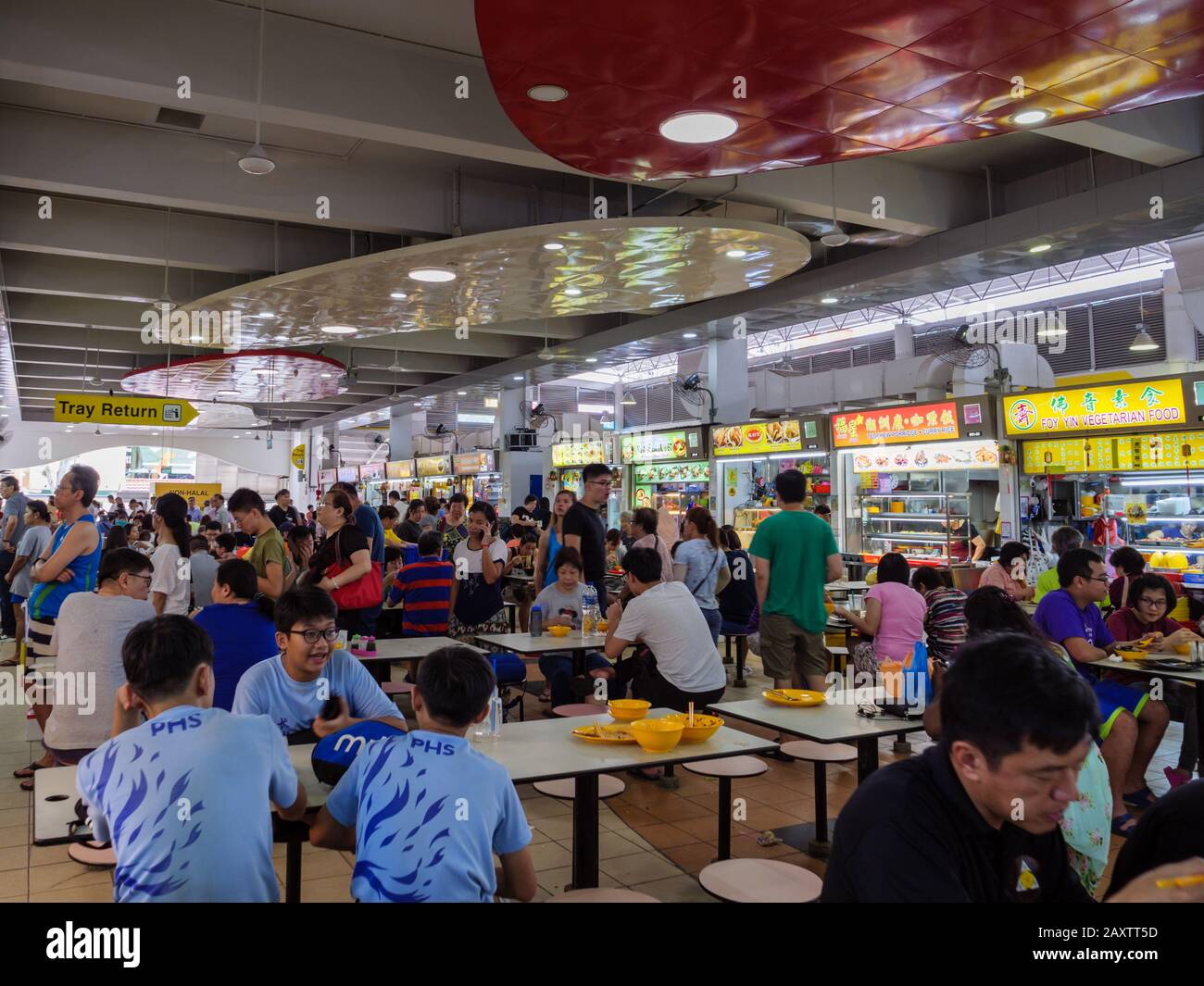 Singapur - 4. JANUAR 2020 - chinesische Diners in Asien, die in einem überfüllten Self-Service-Hawker-Center in Ang Mo Kio, Singapur, Southeas speisen und gesellig sind Stockfoto