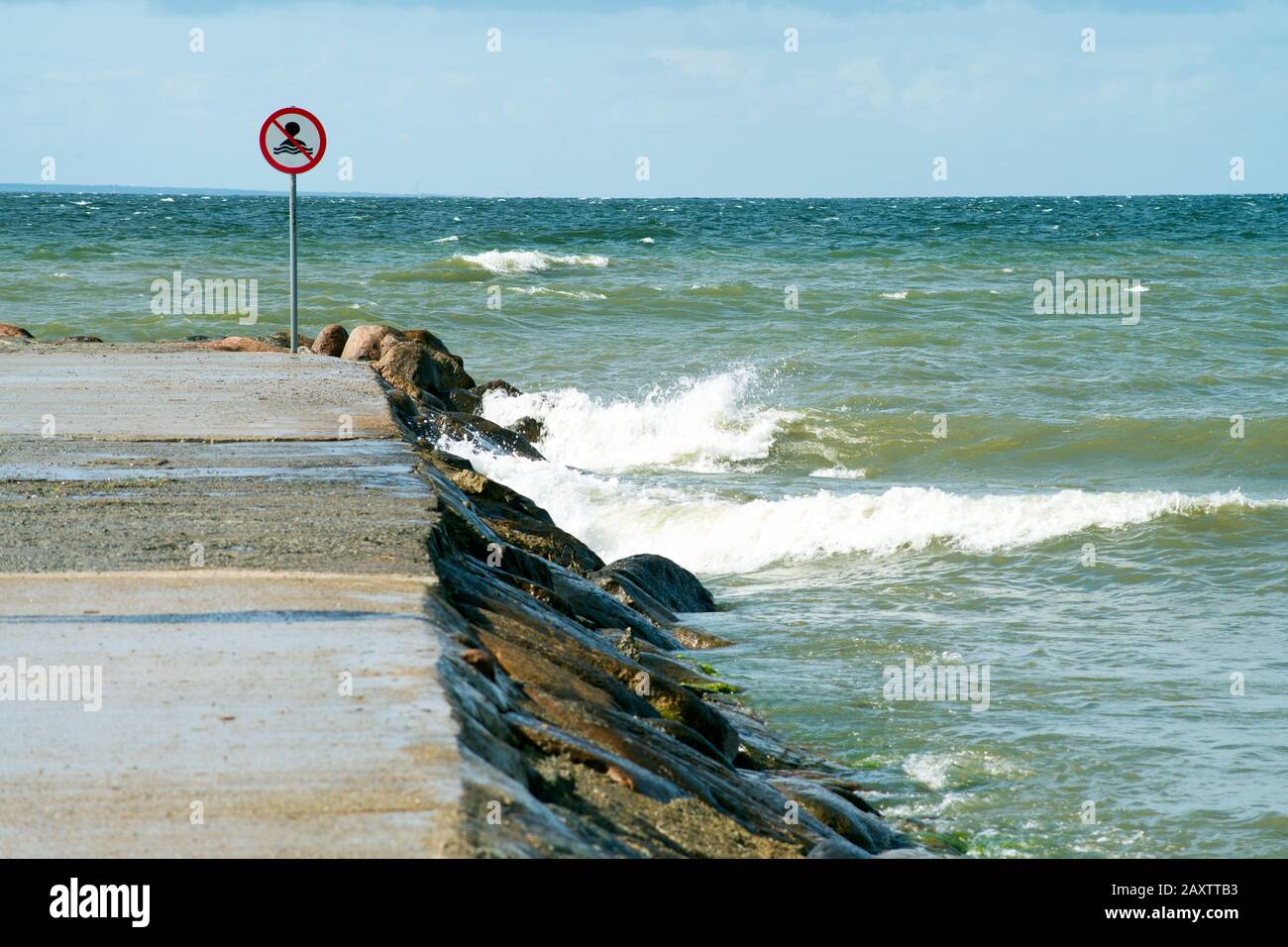 Gefahr, Sperrgebiet, Abzeichen halten. Helles rot-weißes Warnschild an einer felsigen Küste. Bereich für Schwimmeinschränkungen. Riesige Meereswellen groß Stockfoto