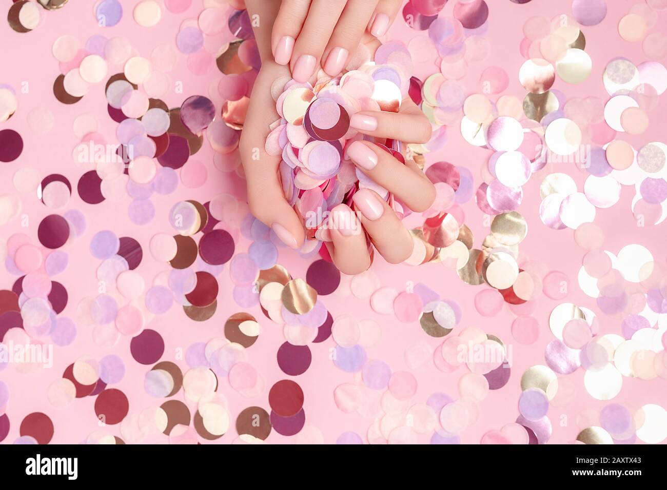 Schöne weibliche Hände mit farbenfrohem Rundpapier, die auf pinkfarbenem Hintergrund gefüllt sind. Flaches Lay. Urlaubskonzept. Kopierbereich. Mockup für Ihr Design. Stockfoto