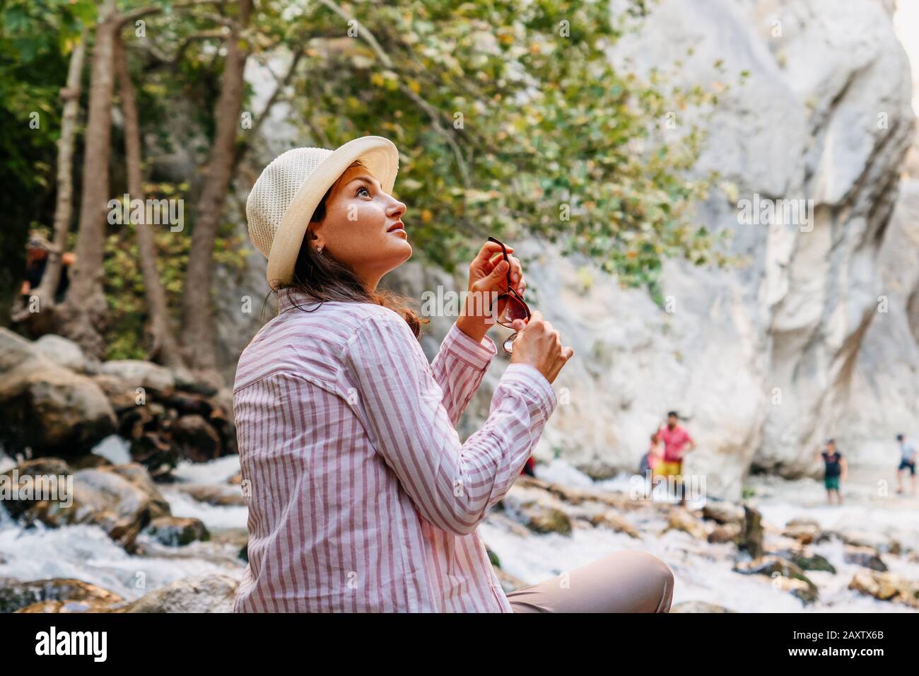 Schöne Touristenfrau, die sitzt und ruht, während sie in der Natur wandert. Wanderlust Konzept Stockfoto