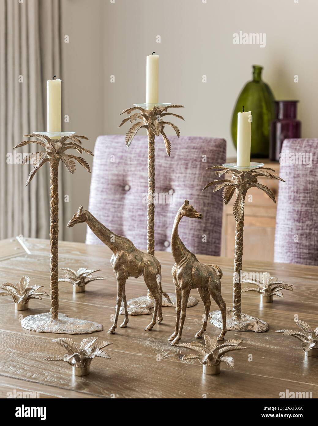 Silberne Kerzenhalter und Giraffenverzierungen auf Esstisch Stockfoto