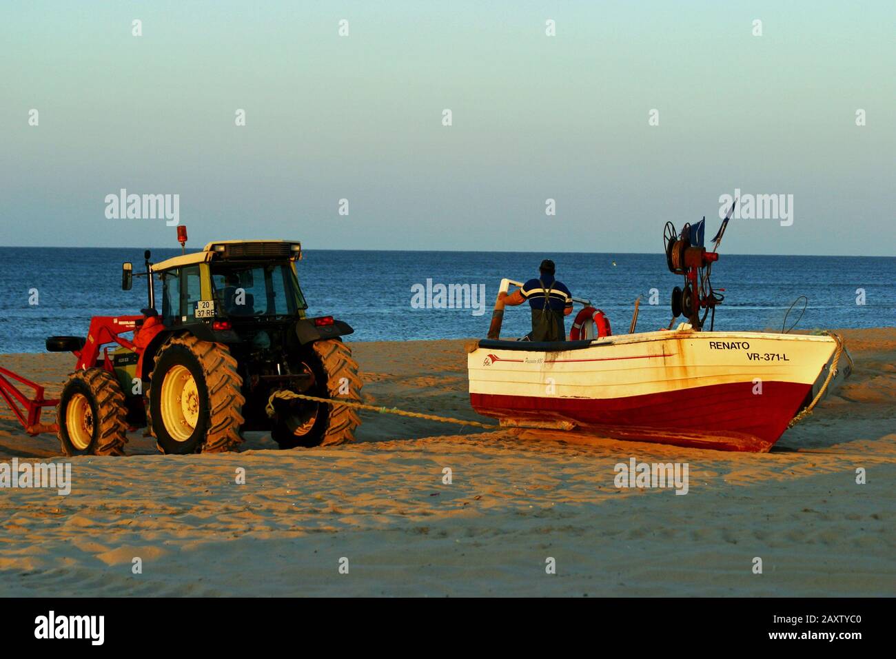 Fischer am frühen Morgen am Strand, der sich auf das Meer vorbereitet. Das Boot wird vom Traktor ins Wasser gezogen. Stockfoto