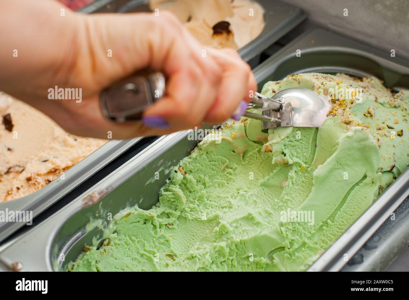 Frau wählt einen Eisball. Pistachio-Eis mit Schaufel. Stockfoto