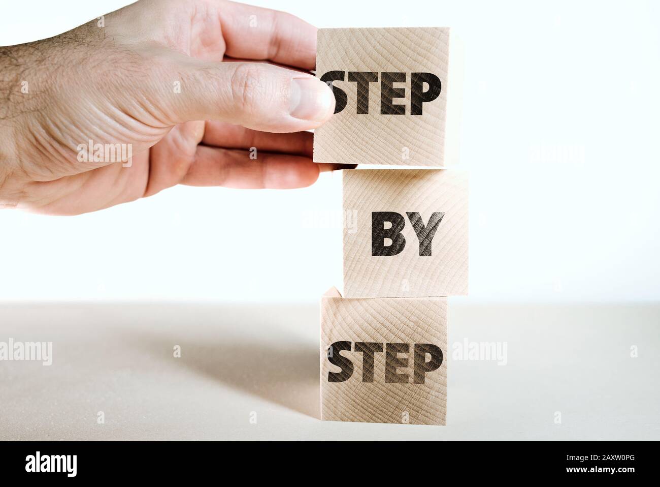 Handstapelbare Holzspielzeugblöcke mit Worten Schritt für Schritt, Wachstums- und Fortschrittskonzept Stockfoto