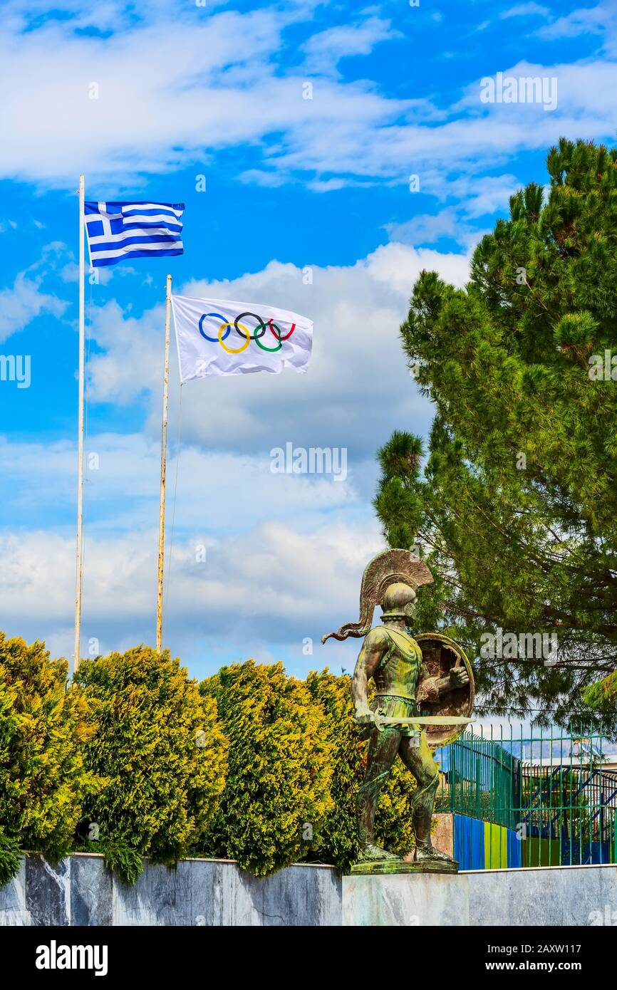 Sparta, Griechenland - 29. März 2019: Statue von Leonidas, König von Sparta auf der Peloponnes mit griechischen und olympischen Fahnen Stockfoto