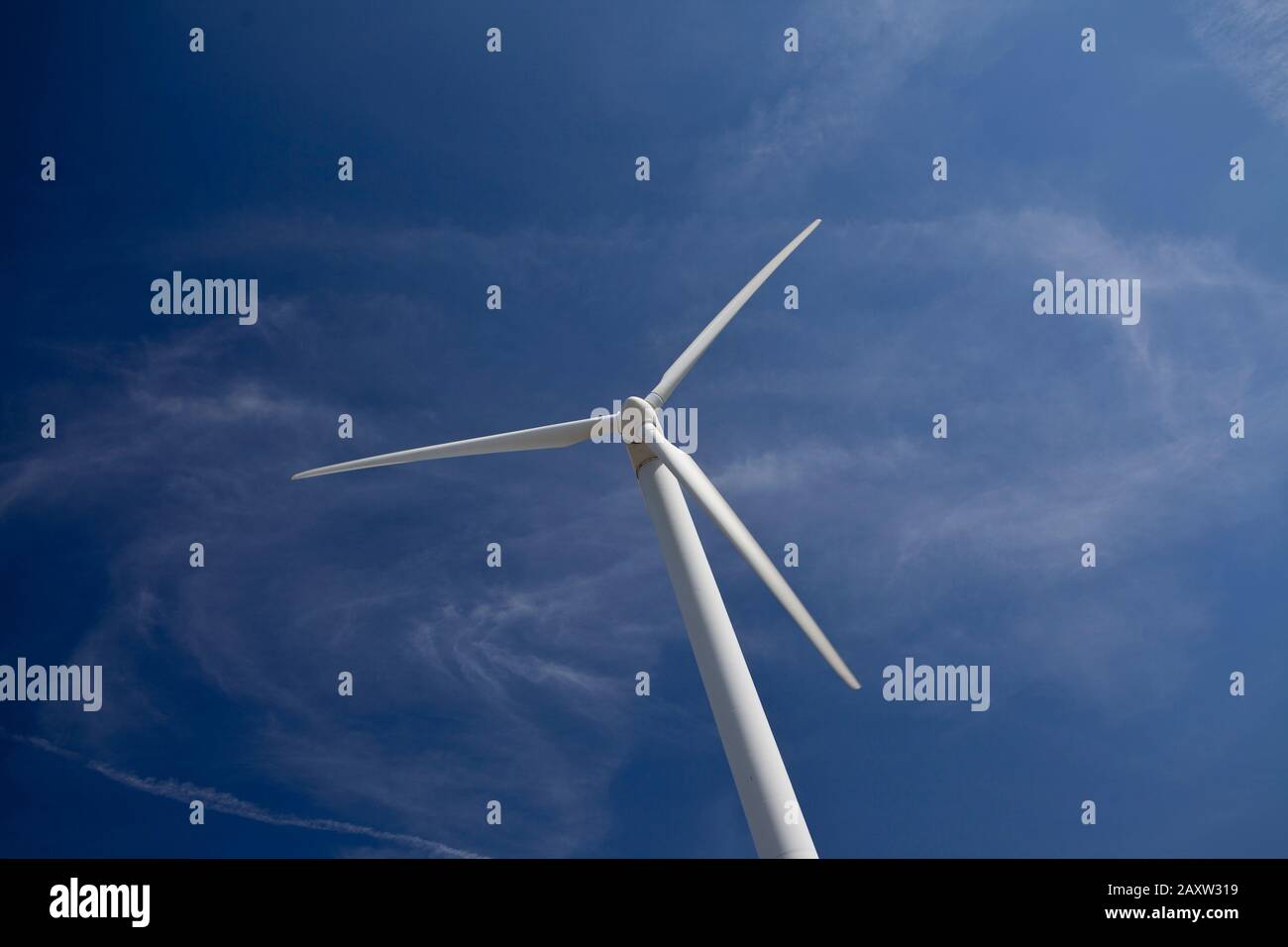 Weiße Windturbine gegen einen perfekten blauen Himmel kleine flauschige weiße Wolken Stockfoto