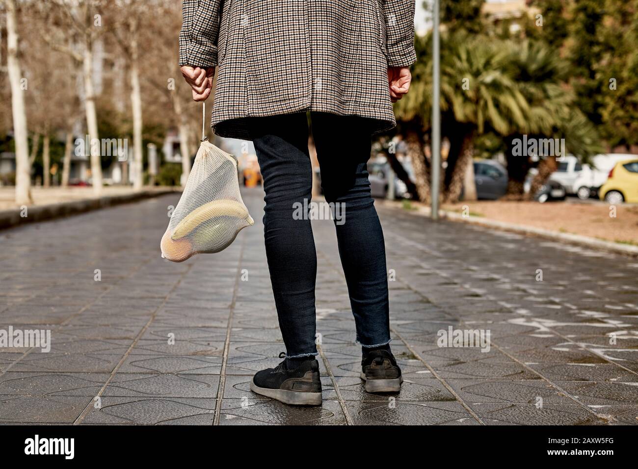 Nahaufnahme eines Mannes auf der Straße, von hinten gesehen, mit einem wiederverwendbaren Netzbeutel aus Textil, der früher Lebensmittel in großen Mengen, voller Obst und Gemüse, kaufte, A. Stockfoto