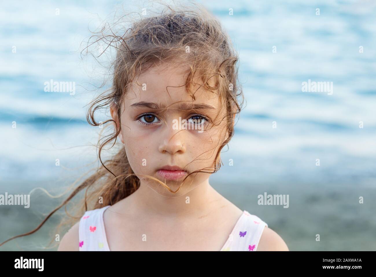 Portrait des süßen traurigen kleinen Mädchens, das am Meer steht Stockfoto